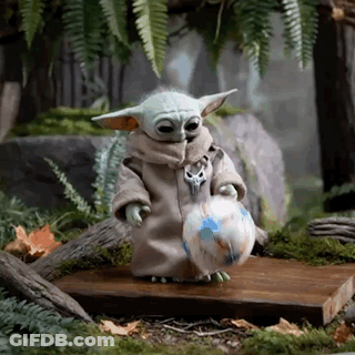 A Baby Yoda Is Holding A Soccer Ball In His Hands . GIF