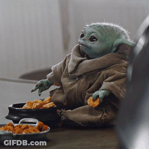 A Baby Yoda Is Sitting At A Table With A Bowl Of Chicken Nuggets GIF