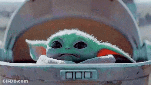 A Baby Yoda Is Sitting In A Trash Can And Looking Out Of It . GIF