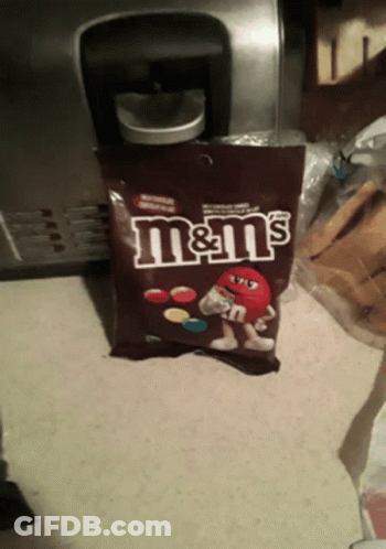 A Bag Of M & M 'S Sits On A Counter In Front Of A Coffee Maker GIF