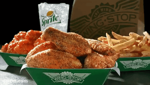 A Bag Of Sprite Sits Next To A Tray Of Chicken Wings And French Fries GIF
