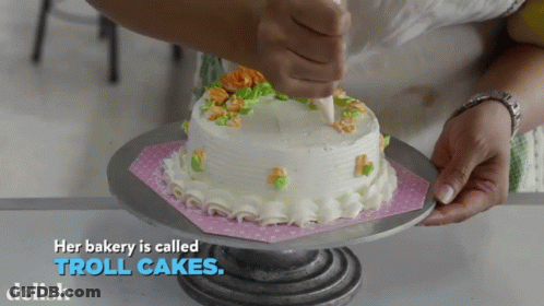 A Bakery Is Called Troll Cakes With A Cake On A Stand GIF