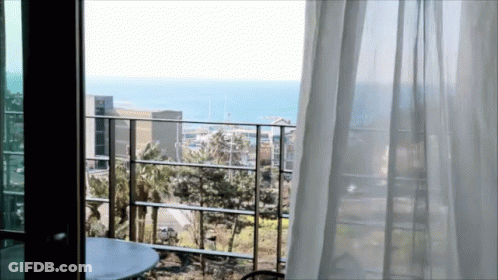 A Balcony With A View Of The Ocean And A Table GIF