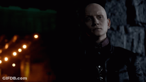 A Bald Man In A Black Jacket Stands In Front Of A Brick Wall GIF