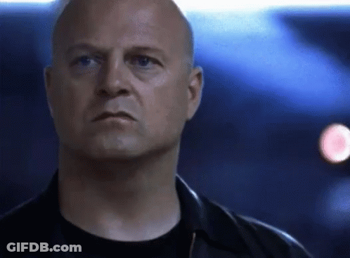A Bald Man In A Black Shirt And Black Jacket Looks At The Camera GIF