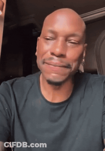 A Bald Man In A Black Shirt Is Smiling GIF