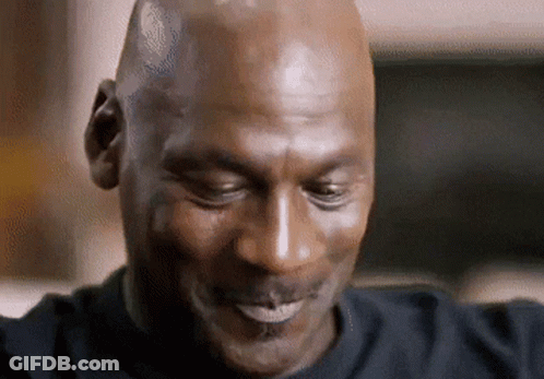 A Bald Man In A Black Shirt Is Smiling With His Eyes Closed GIF