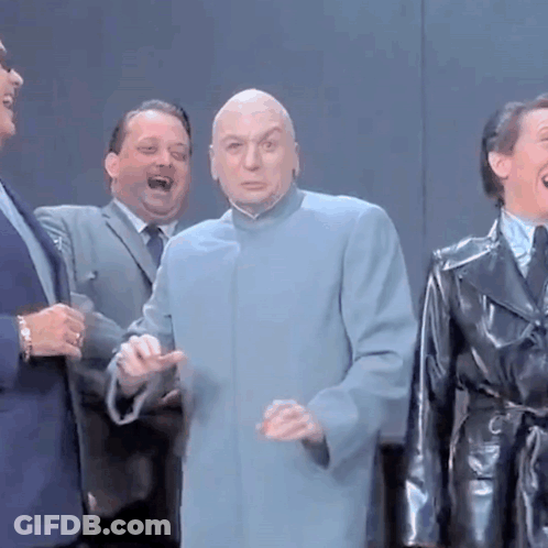A Bald Man In A Blue Coat Is Standing In A Group Of Men GIF