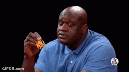 A Bald Man In A Blue Shirt Is Holding A Piece Of Cheese In His Hand . GIF