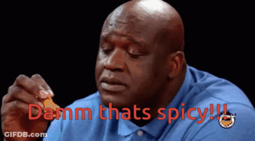 A Bald Man In A Blue Shirt Is Holding A Piece Of Food And Says " Damn Thats Spicy " In Red GIF