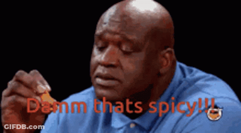 A Bald Man In A Blue Shirt Is Holding A Piece Of Food With The Words " Damn Thats Spicy " Above Him GIF