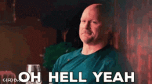 A Bald Man In A Blue Shirt Is Sitting At A Table With A Glass Of Wine And Says `` Oh Hell Yeah '' . GIF