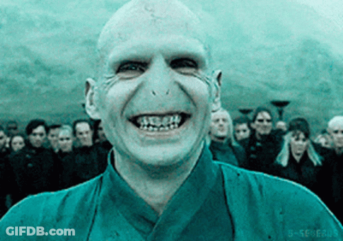 A Bald Man In A Blue Shirt Is Smiling In Front Of A Crowd Of People GIF