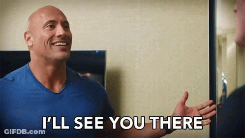 A Bald Man In A Blue Shirt Is Standing In Front Of A Mirror And Smiling . GIF
