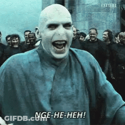 A Bald Man In A Blue Shirt Says Nge-He-Heh In Front Of A Crowd GIF