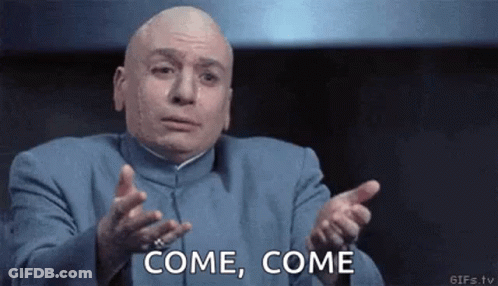 A Bald Man In A Blue Suit Is Making A Funny Face And Pointing At The Camera . GIF
