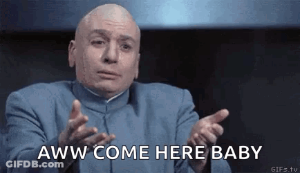 A Bald Man In A Blue Suit Is Making A Funny Face And Pointing At The Camera . GIF