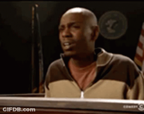 A Bald Man In A Brown And Tan Jacket Is Sitting At A Keyboard GIF