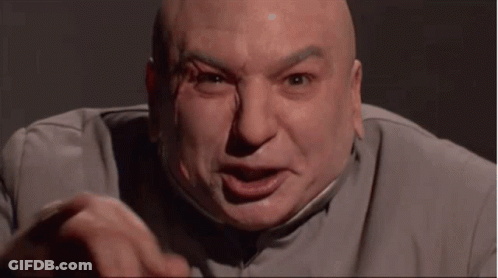 A Bald Man In A Gray Suit Is Making A Funny Face And Pointing At The Camera . GIF