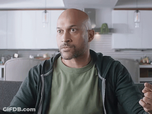 A Bald Man In A Green Shirt And Black Hoodie GIF
