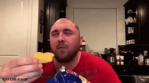 A Bald Man In A Red Shirt Eating A Bag Of Chips GIF