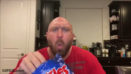 A Bald Man In A Red Shirt Is Eating A Bag Of Chips GIF