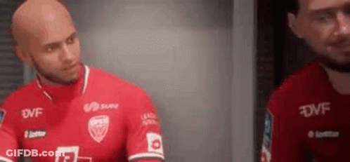 A Bald Man In A Red Soccer Jersey Is Standing Next To Another Bald Man In A Red Jersey . GIF
