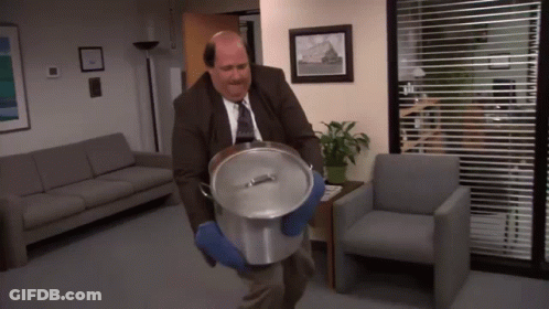 A Bald Man In A Suit And Tie Is Carrying A Pot GIF