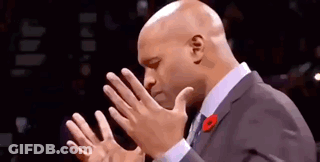 A Bald Man In A Suit And Tie Is Clapping His Hands Together . GIF