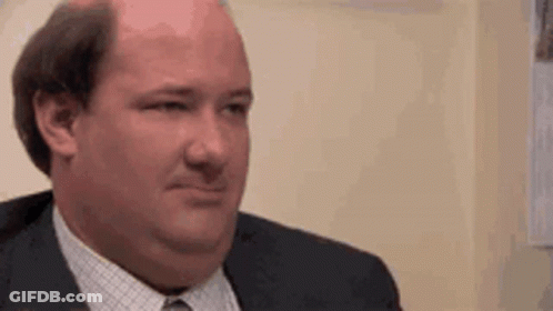 A Bald Man In A Suit And Tie Is Making A Face . GIF