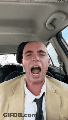 A Bald Man In A Suit And Tie Is Screaming In The Back Seat Of A Car GIF