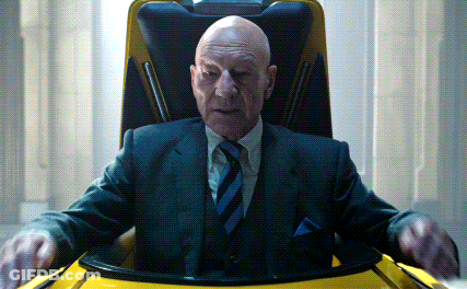 A Bald Man In A Suit And Tie Is Sitting In A Chair GIF