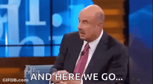 A Bald Man In A Suit And Tie Is Sitting On A Stage Talking On A Talk Show . GIF