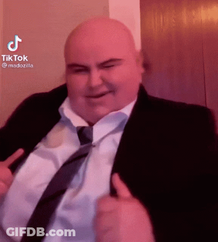 A Bald Man In A Suit And Tie Is Smiling And Giving A Thumbs Up GIF