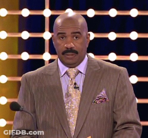 A Bald Man In A Suit And Tie Is Speaking Into A Microphone GIF