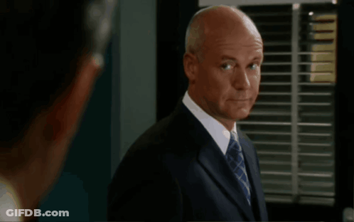 A Bald Man In A Suit And Tie Stands In Front Of A Screen That Says Get Over It GIF