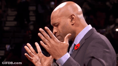 A Bald Man In A Suit And Tie With A Poppy Pin On His Lapel GIF