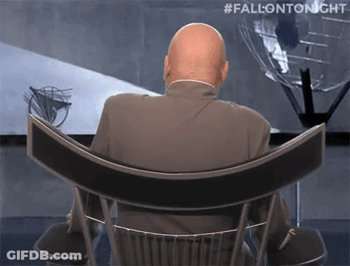 A Bald Man In A Suit Is Sitting In A Chair With His Back To The Camera And #Fallontonight Written Above Him . GIF