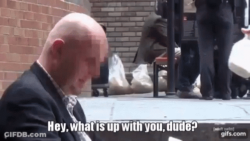 A Bald Man In A Suit Is Sitting On The Sidewalk And Says Hey What Is Up With You Dude GIF