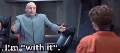 A Bald Man In A Suit Is Talking To A Young Boy In An Orange Jacket . GIF