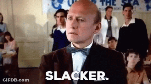 A Bald Man In A Tuxedo And Bow Tie Is Standing In Front Of A Group Of People . GIF