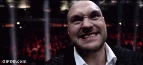 A Bald Man In A White Shirt Is Smiling In Front Of A Crowd GIF