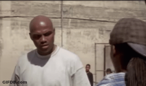 A Bald Man In A White Shirt Is Talking To A Woman In A Hat . GIF