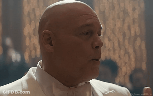 A Bald Man In A White Tuxedo And Bow Tie Is Talking GIF