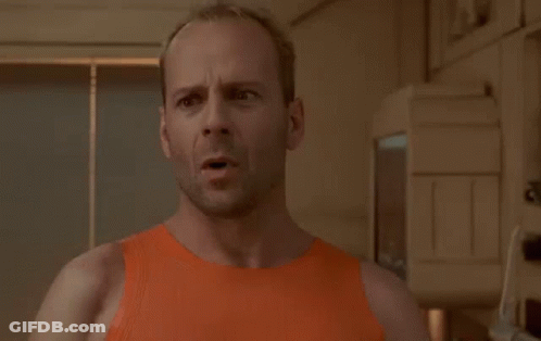 A Bald Man In An Orange Tank Top Is Standing In Front Of A Sign That Says I Am Not Going GIF