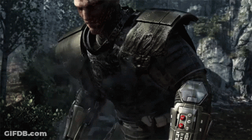 A Bald Man In Armor Stands In Front Of A Rocky Cliff GIF