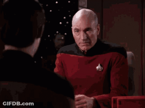 A Bald Man Is Covering His Face With His Hands While Another Man Looks On GIF