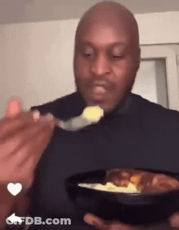 A Bald Man Is Eating Food With A Spoon From A Bowl . GIF