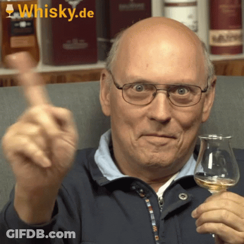 A Bald Man Is Holding A Glass Of Whisky And Giving A Thumbs Up Sign GIF
