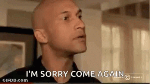 A Bald Man Is Saying `` I 'M Sorry Come Again '' While Standing In A Living Room . GIF